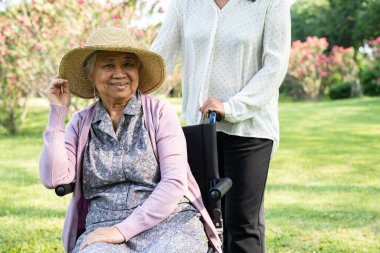 Caregiver help and care Asian elderly woman use walker with strong health while walking at park in happy fresh holiday.
