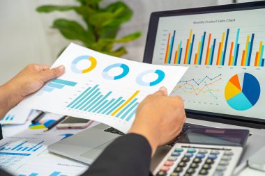 Modern ofis, finans ve iş konsepti grafikleriyle muhasebe projesini inceleyen Asyalı muhasebeci.