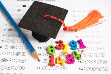 Cevap kağıdındaki mezuniyet şapkası ve kalem boşluğu, eğitim eğitimi sınavı öğrenme konsepti.