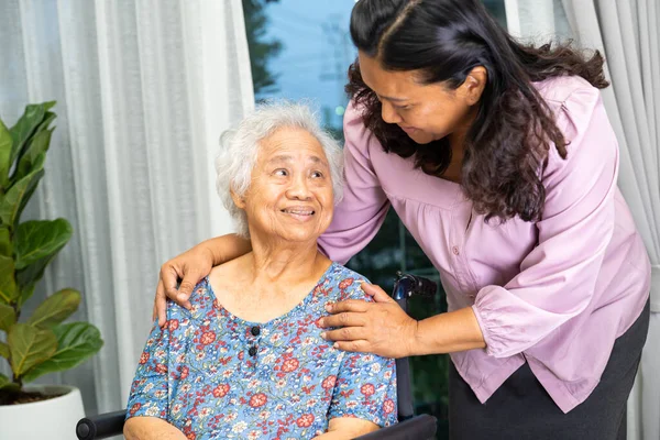 Caregiver help Asian senior woman on wheelchair with love at home.