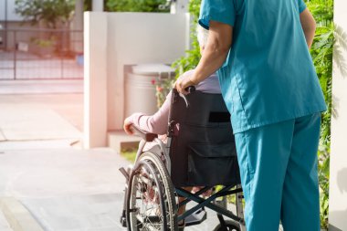 Bakıcı yardım ve bakım Asyalı yaşlı kadın hasta tekerlekli sandalyede hemşire hastanesinde rampaya oturuyor, sağlıklı güçlü tıbbi konsept..