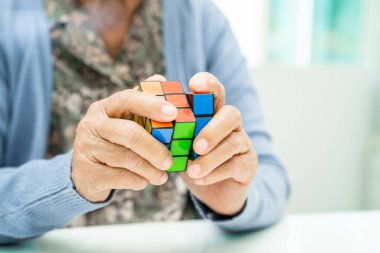 BANGKOK, THAILAND 11 HAZİRAN 2023 Alzheimer hastalığı AD, bunama için beyin antrenmanı yapmak amacıyla Rubik küp oyunu oynayan Asyalı yaşlı kadın hasta.