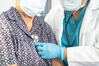 Doktor, hastayı kontrol etmek için steteskop kullanıyor. Hastanedeki bir yatağa uzanıyor. Sağlıklı, güçlü bir tıbbi konsept..