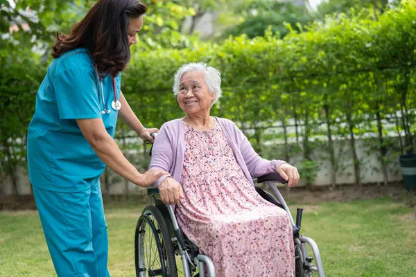Doctor help and care Asian senior woman patient sitting on wheelchair at park in nursing hospital ward, healthy strong medical concept.
