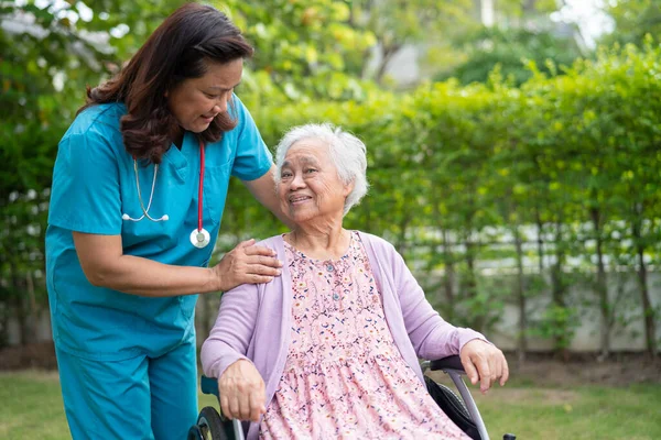 Doctor help and care Asian senior woman patient sitting on wheelchair at park in nursing hospital ward, healthy strong medical concept.