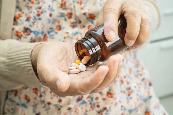 薬局の薬局の概念の処置の患者のための抗生物質のカプセルの丸薬を握っているアジアのシニアの女性の患者 — ストック写真