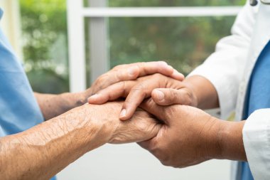 Caregiver holding hands Asian elderly woman patient with love, care, encourage and empathy at nursing hospital, healthy strong medical concept.
