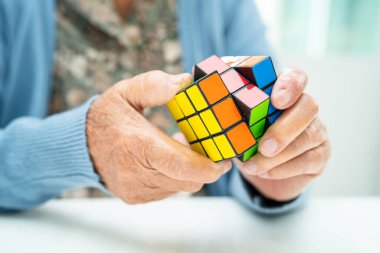 Bangkok, Tayland 14 Ağustos, 2023 Alzheimer Hastalığı AD, Asyalı yaşlı kadın hasta bunama için beyin eğitimi için Rubik küp oyunu oynuyor..