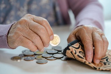 Asyalı son sınıf öğrencisi kadın çantasından bozuk para sayıyor. Yoksulluk, emeklilikte tasarruf sorunu.