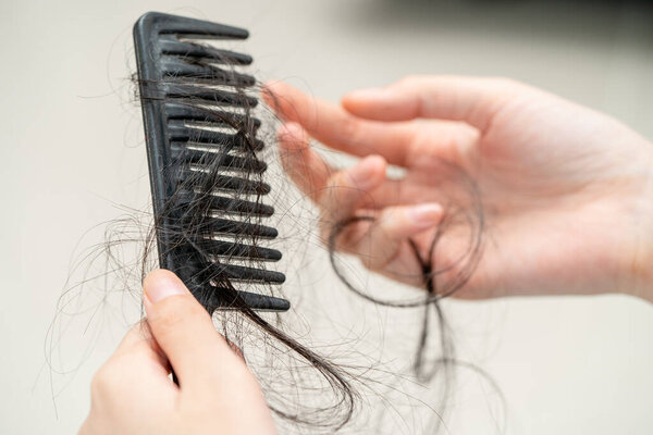 Asian woman have problem with long hair loss attach to comb brush.