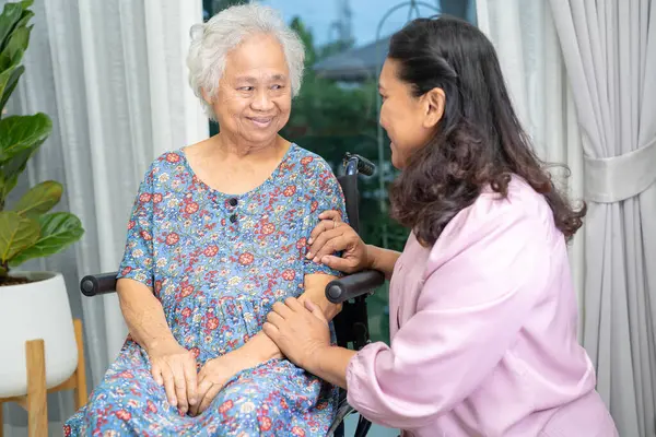 Caregiver help Asian senior woman on wheelchair with love at home.