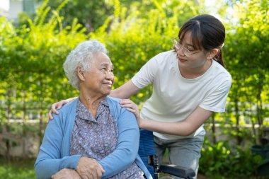 Caregiver help and care Asian elderly woman use walker with strong health while walking at park in happy fresh holiday.