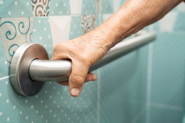 Asyalı yaşlı kadın tuvalette tuvalet tutacağı kullanıyor. Sağlıklı güçlü tıbbi konsept..