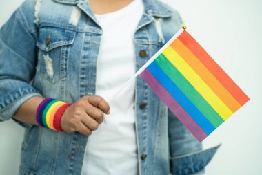 Gökkuşağı bilekliği takan Asyalı kadın ve kırmızı kalp, LGBT onur ayının sembolü, Haziran sosyal ortamında eşcinsel, lezbiyen, biseksüel, transseksüel, insan hakları kutlamaları.