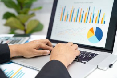 Modern ofis, finans ve iş konseptinde grafik grafik grafiği ve hesap makinesiyle çalışan ve finansal raporları analiz eden Asyalı muhasebeci.