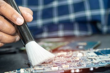 Asian technician repair and cleaning dirty micro circuit main board of smartphone electronic technology with brush, hardware, mobile phone, upgrade concept.