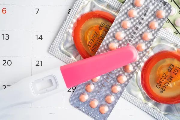 Pregnancy test and birth control pills on calendar, contraception health and medicine.