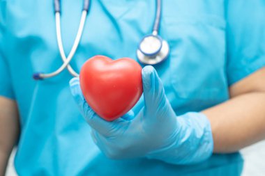 Hastane koğuşunda kırmızı kalp tutan bir doktor, sağlıklı güçlü tıbbi konsept..