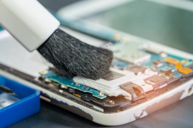 Asyalı teknisyen fırça, donanım, cep telefonu, güncelleme ile akıllı telefon elektronik teknolojisinin kirli mikro devre tamiri ve temizliği.