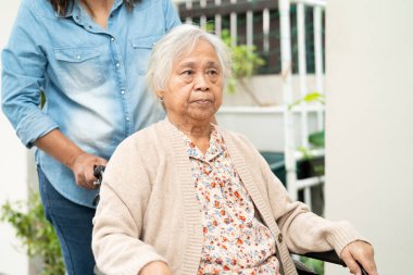 Bakıcı yardım ve bakım Asyalı yaşlı kadın hasta tekerlekli sandalyede hemşirelik hastanesinde rampaya oturuyor, sağlıklı ve güçlü bir tıbbi tedavi..
