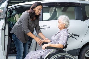 Caregiver help and support asian elderly woman sitting on wheelchair prepare get to her car to travel in holiday.