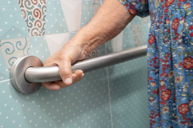 Asyalı yaşlı bir kadın tuvalette tuvalet tutacağı kullanıyor. Sağlıklı, güçlü bir tıbbi tedavi..