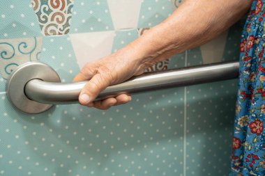 Asyalı yaşlı bir kadın tuvalette tuvalet tutacağı kullanıyor. Sağlıklı, güçlü bir tıbbi tedavi..