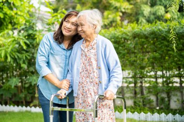 Doktor bakıcı, son sınıf Asyalı hasta Walker 'la birlikte hastanede yürüyor..