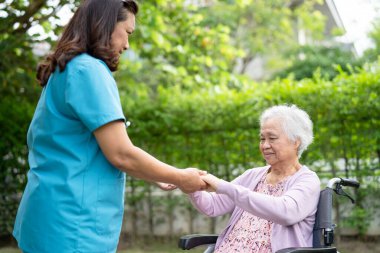 Doktor yardımı ve bakımı Asyalı yaşlı kadın hasta. Parkta, hemşire hastanesi koğuşunda tekerlekli sandalyede oturuyor. Sağlıklı, güçlü bir tıbbi konsept..