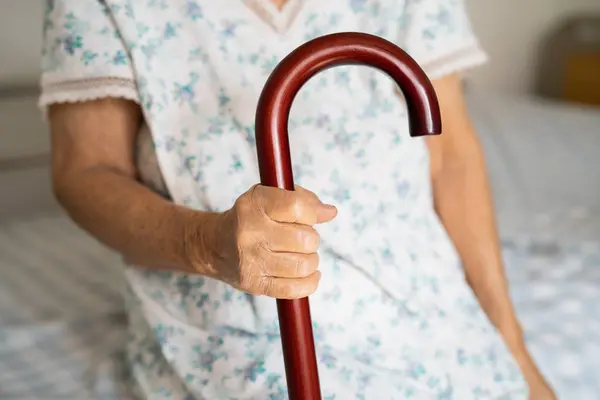 stock image Asian elderly disability woman holding waling stick, wood cane, round handle, walking aid for help to walk.