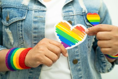Gökkuşağı bilekliği takan Asyalı kadın ve kırmızı kalp, LGBT onur ayının sembolü, Haziran sosyal ortamında eşcinsel, lezbiyen, biseksüel, transseksüel, insan hakları kutlamaları.