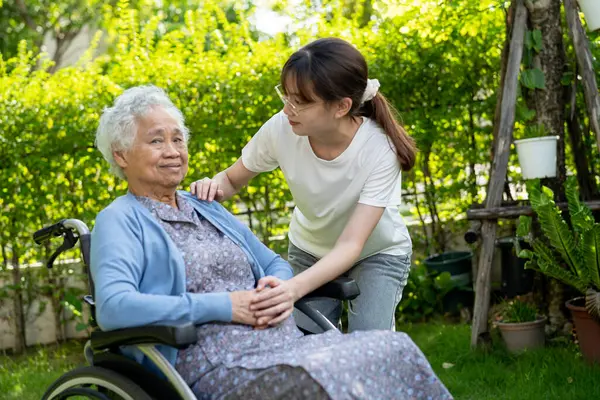 Bakıcı yardım ve bakım Asyalı yaşlı kadın hasta hemşire hastanesi koğuşunda tekerlekli sandalyede oturuyor, sağlıklı ve güçlü..