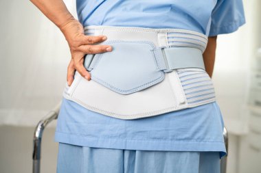 Ortopedik bel kemiği için sırt ağrısı destek kemeri takan Asyalı bir hasta..