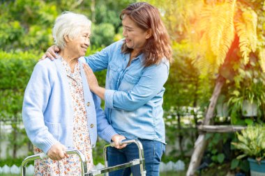 Doktor bakıcı, son sınıf Asyalı hasta Walker 'la birlikte hastanede yürüyor..