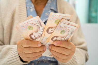 Tayland 'da elinde para tutan Asyalı yaşlı bir kadın. Yoksulluk, emeklilikte tasarruf sorunu.