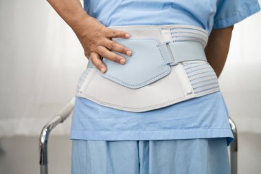 Ortopedik bel kemiği için sırt ağrısı destek kemeri takan Asyalı bir hasta..