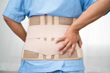 Ortopedik bel kemiği için sırt ağrısı destek kemeri takan Asyalı bir hasta..