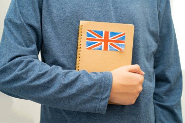 İngilizce öğren, Asyalı ergen öğrenci okulda bayraklı kitap tutuyor..