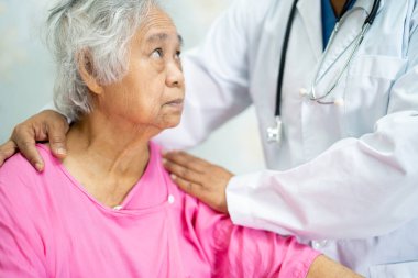 Doktor, Asyalı yaşlı kadına hastanede sevgi, ilgi, yardım, cesaret ve empati ile yardım edin..