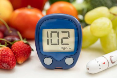 Asya 'da el ele tutuşan dijital glikoz monitörü sebze ve meyveli sağlıklı gıda ölçümü.