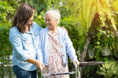 Doktor bakıcı, son sınıf Asyalı hasta Walker 'la birlikte hastanede yürüyor..