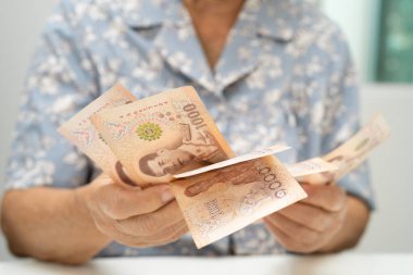 Tayland 'da elinde para tutan Asyalı yaşlı bir kadın. Yoksulluk, emeklilikte tasarruf sorunu.