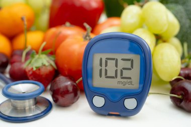 Asya 'da el ele tutuşan dijital glikoz monitörü sebze ve meyveli sağlıklı gıda ölçümü.