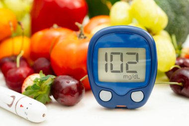 Asya 'da el ele tutuşan dijital glikoz monitörü sebze ve meyveli sağlıklı gıda ölçümü.