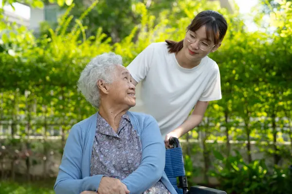 Bakıcı yardım ve bakım Asyalı yaşlı kadın hasta hemşire hastanesi koğuşunda tekerlekli sandalyede oturuyor, sağlıklı ve güçlü..