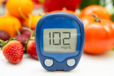 Asya 'da el ele tutuşan dijital glikoz monitörü sebze ve meyveli sağlıklı gıda ölçümü.