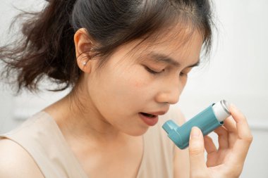 Asyalı kadın astım ve kronik obstrüktif akciğer hastalığı kullanıyor. COPD, Asyalı genç adam ölçülü doz solunum cihazı kullanıyor..