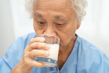 Kahvaltıda süt içen Asyalı yaşlı kadın..