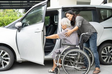 Caregiver help and support asian elderly woman sitting on wheelchair prepare get to her car to travel in holiday.