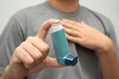 Astım ve kronik obstrüktif akciğer hastalığı COPD, Asyalı genç adam ölçülü doz solunum cihazı kullanıyor..